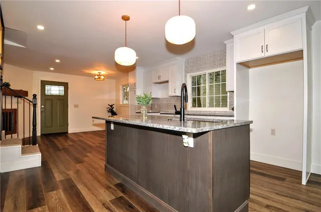a kitchen with granite countertop a stove a sink and a wooden floors