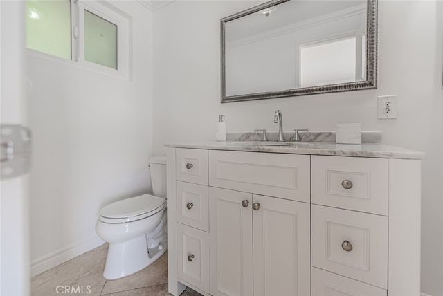a bathroom with a granite countertop toilet sink and mirror