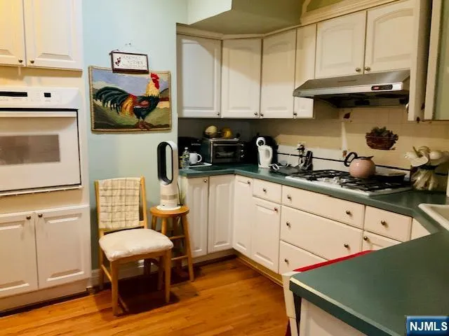 a kitchen with stainless steel appliances a stove a sink cabinets and wooden floor