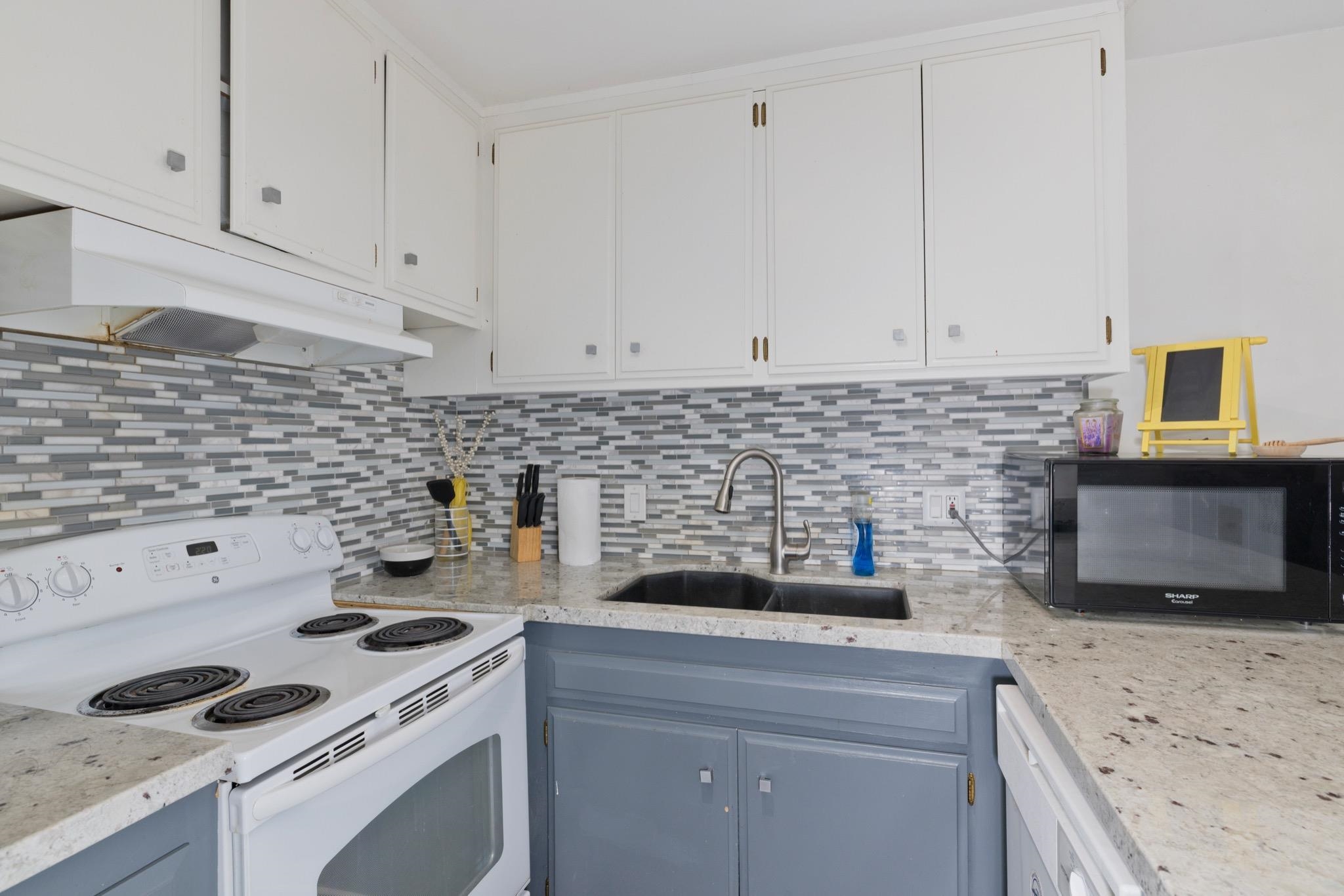 165 Old Mammoth Road, Unit 13 Mammoth Lakes, CA 93546 - Photo 12 of 23 Modern kitchen featuring white upper cabinetry, gray lower cabinetry, and a mosaic tile backsplash