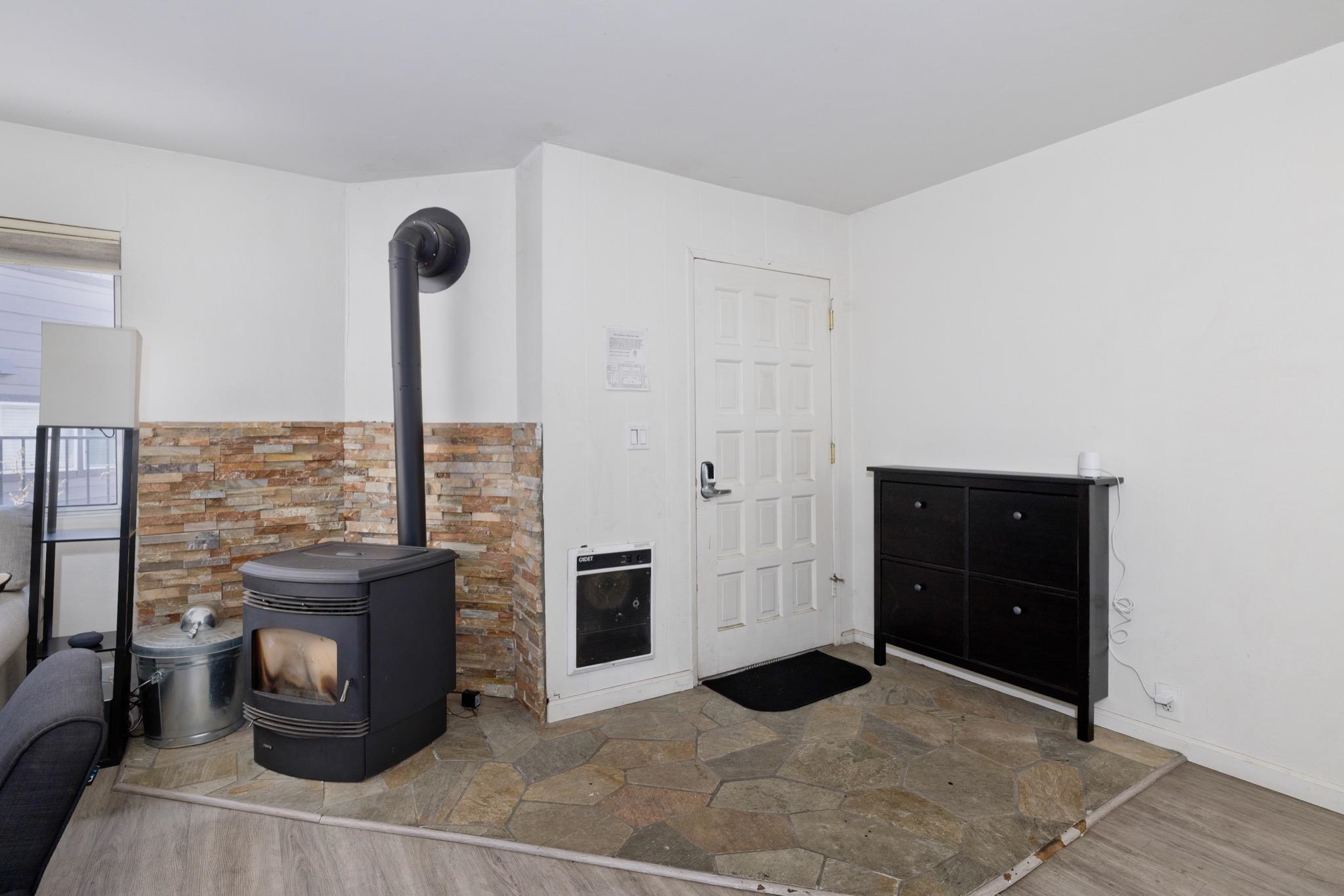 165 Old Mammoth Road, Unit 13 Mammoth Lakes, CA 93546 - Photo 4 of 23 Freestanding wood-burning stove with a stone veneer surround, featuring a flagstone entry area and a paneled entry door