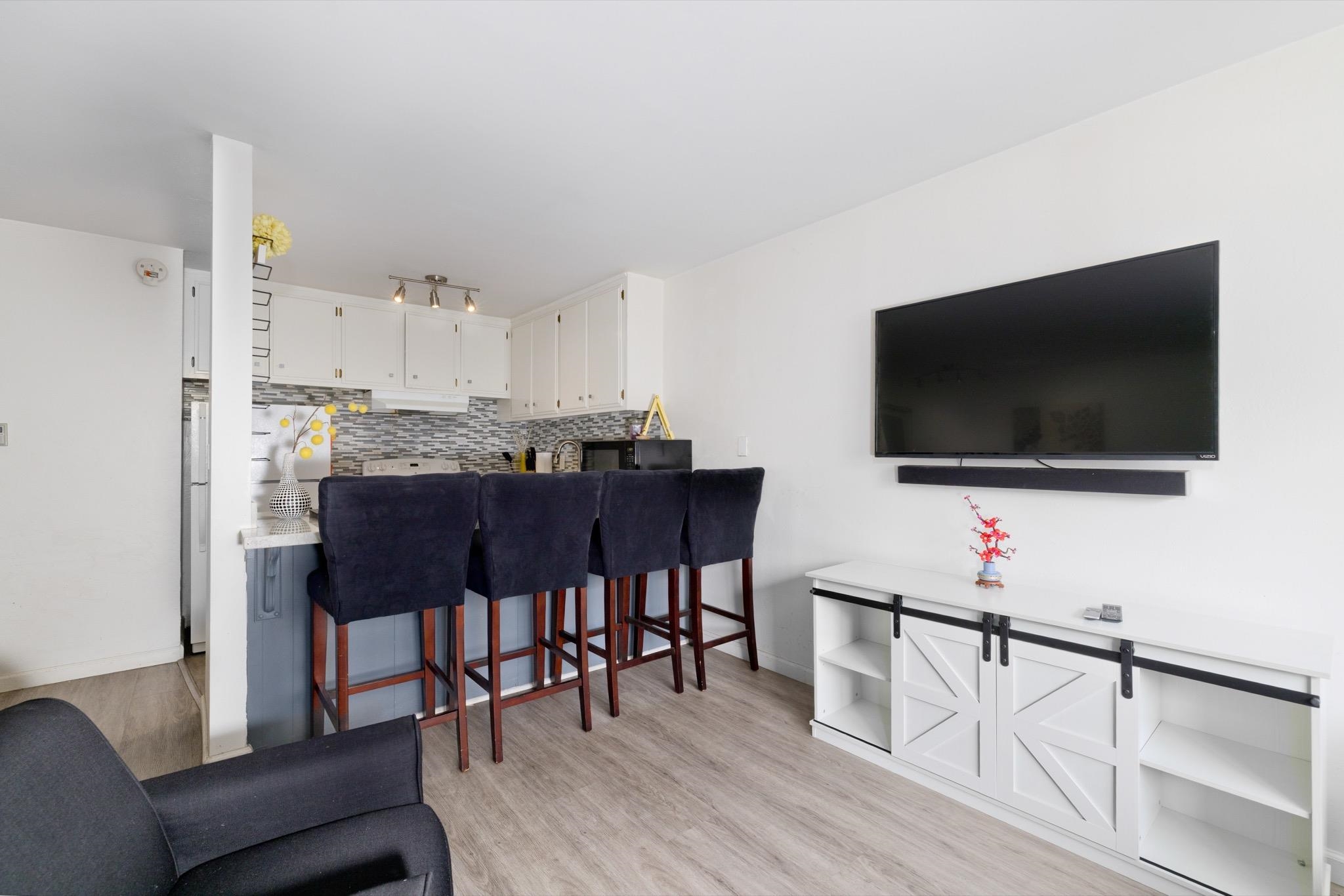 165 Old Mammoth Road, Unit 13 Mammoth Lakes, CA 93546 - Photo 7 of 23 Open-concept living area featuring wood-finish flooring, white walls, and a dedicated entertainment wall