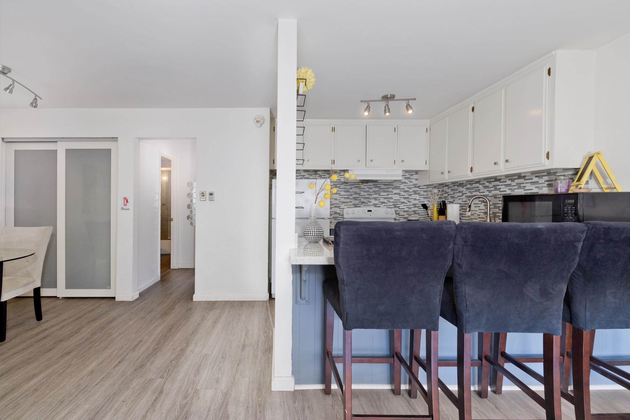 165 Old Mammoth Road, Unit 13 Mammoth Lakes, CA 93546 - Photo 9 of 23 Kitchen featuring white cabinetry, a mosaic tile backsplash, a stainless steel sink with a gooseneck faucet, and a breakfast bar with a light-toned countertop