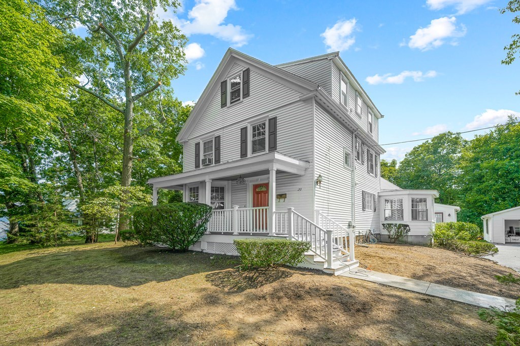 a view of a white house next to a yard with big trees
