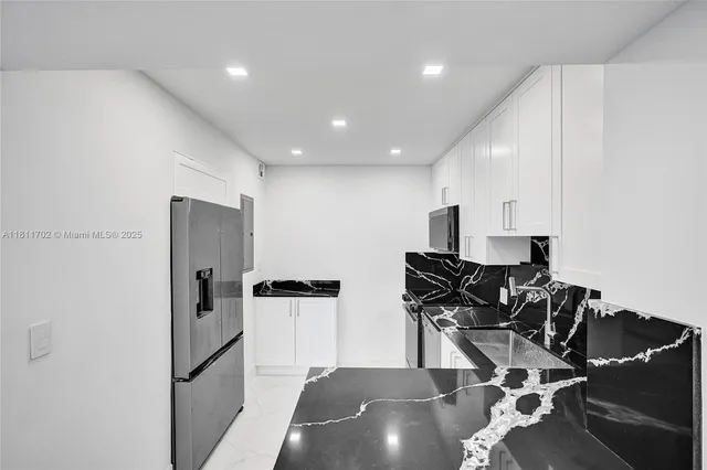 a kitchen with stainless steel appliances granite countertop a refrigerator and a stove top oven with wooden floor