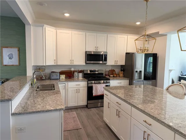 a kitchen with granite countertop a sink stainless steel appliances and white cabinets