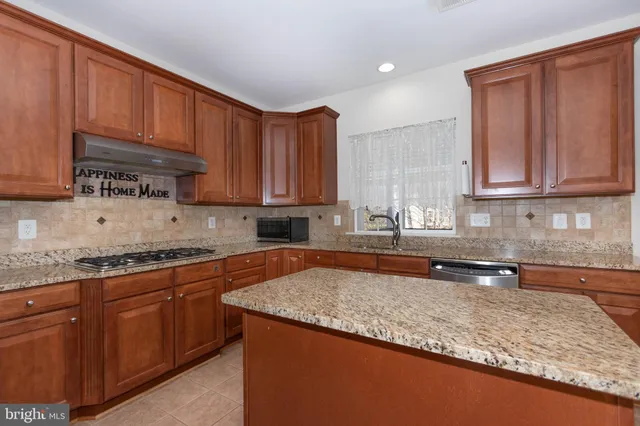 a kitchen with stainless steel appliances granite countertop a stove a sink dishwasher and a refrigerator with wooden cabinets