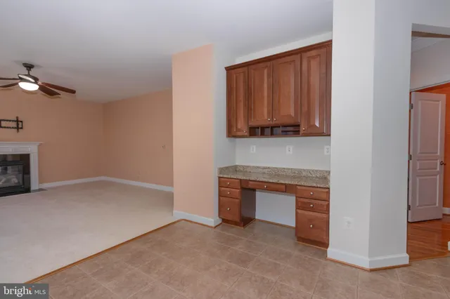 a view of an empty room with a window and a kitchen