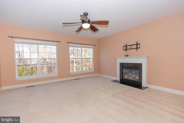 an empty room with chandelier fan and windows