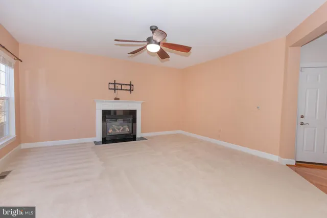 a view of a livingroom with a ceiling fan and kitchen space