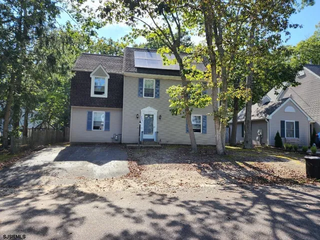 a front view of a house with a dirt yard and a large tree