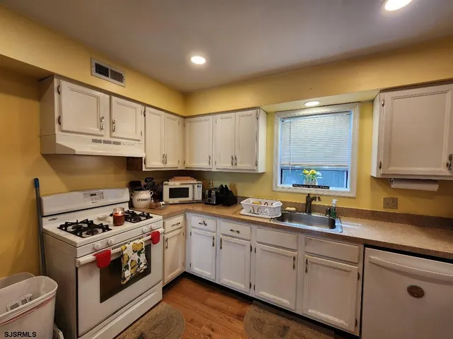a kitchen with granite countertop a sink a stove and cabinets