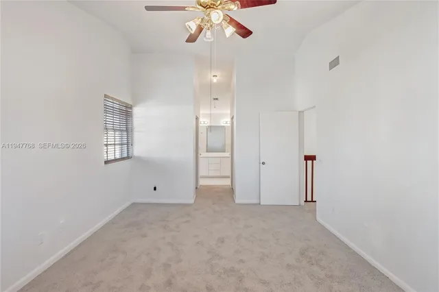 an empty room with chandelier fan and windows