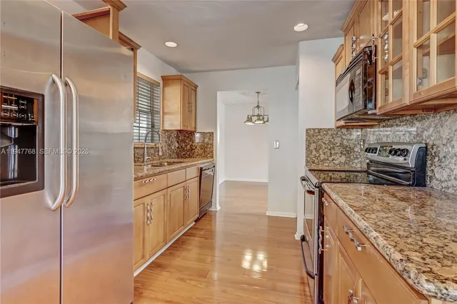 a kitchen with stainless steel appliances granite countertop a refrigerator a stove and a sink