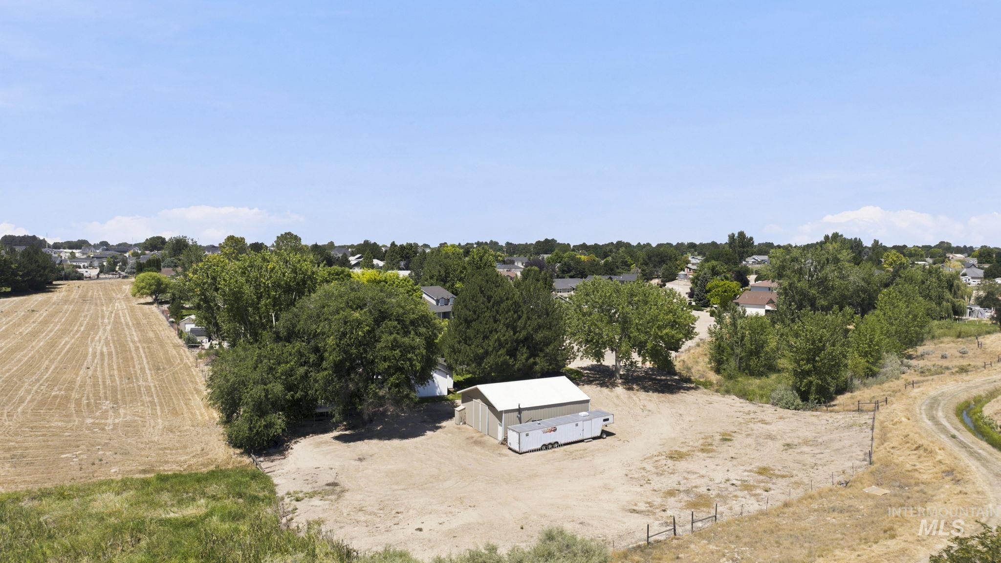 24864 Coventry Drive Caldwell, ID 83607 - Photo 30 of 49 Expansive lot featuring a single building with a light-colored roof, surrounded by mature trees and open land
