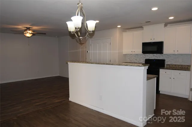 a kitchen with a chandelier stainless steel appliances and wooden floor