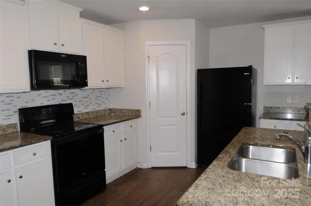 a kitchen with granite countertop a refrigerator stove and microwave