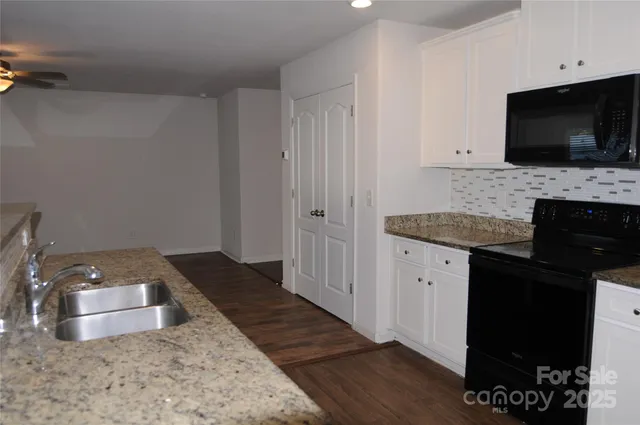 a kitchen with granite countertop a stove and a flat screen tv