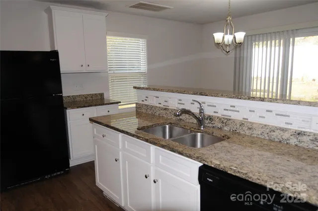 a kitchen with granite countertop a sink dishwasher a refrigerator and cabinets with wooden floor
