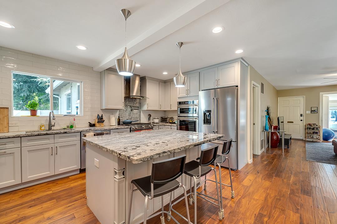 1197 Broadleaf Lane San Jose, CA 95128 - Photo 5 of 29 a kitchen with stainless steel appliances granite countertop a table chairs sink refrigerator and microwave