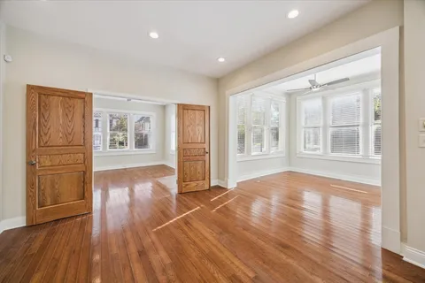 a view of empty room with wooden floor and fan