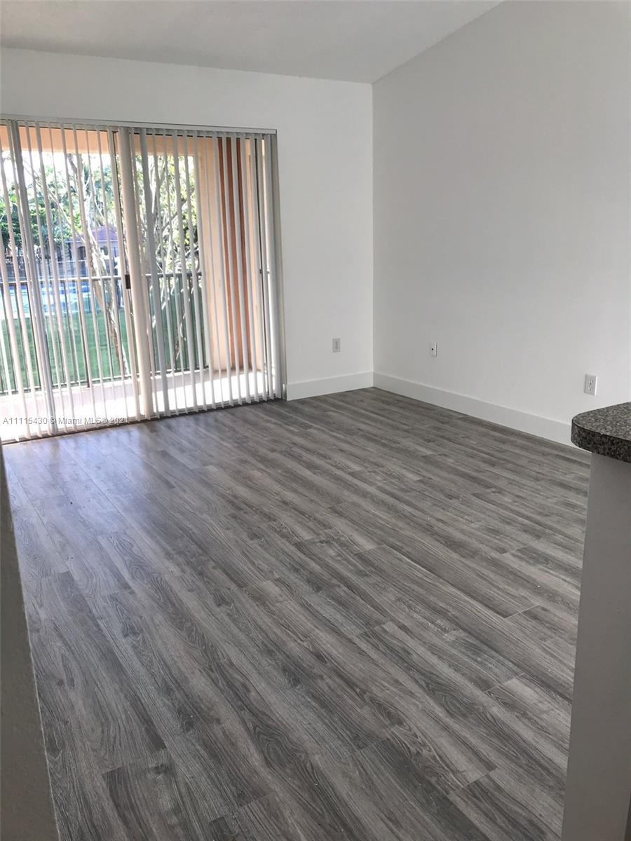 8020 North Nob Hill Road, Unit 208 Tamarac, FL 33321 - Photo 5 of 15 wooden floor in an empty room with a window
