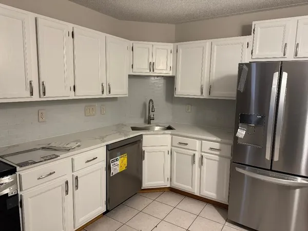 a kitchen with white cabinets and refrigerator