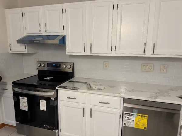 a kitchen with stainless steel appliances granite countertop a stove a sink and a white cabinets