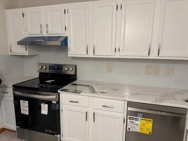 a kitchen with stainless steel appliances granite countertop a stove a sink and a white cabinets