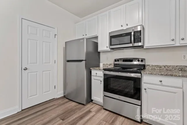 a kitchen with stainless steel appliances white cabinets a stove a microwave and a refrigerator