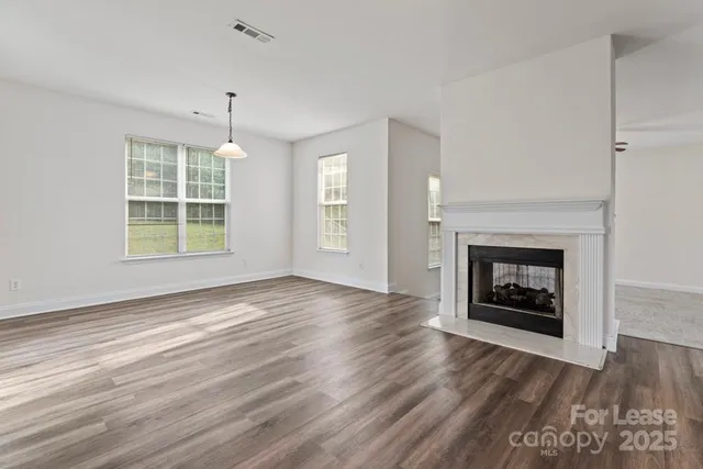 an empty room with windows a fireplace and wooden floor
