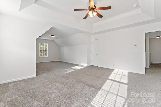 an empty room with chandelier fan and windows