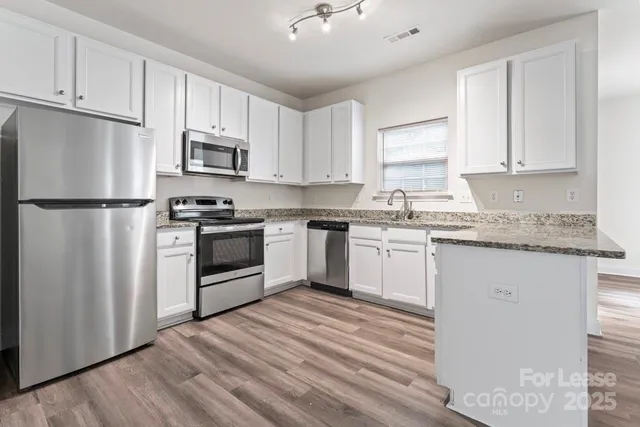a kitchen with granite countertop white cabinets and white appliances
