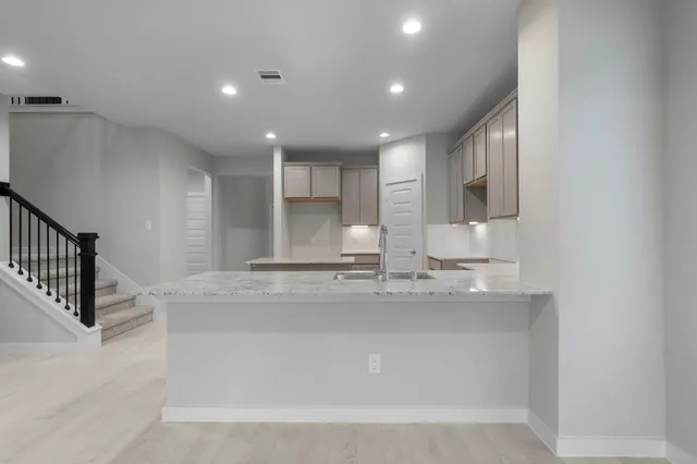 a view of a kitchen with kitchen island a sink stainless steel appliances and cabinets