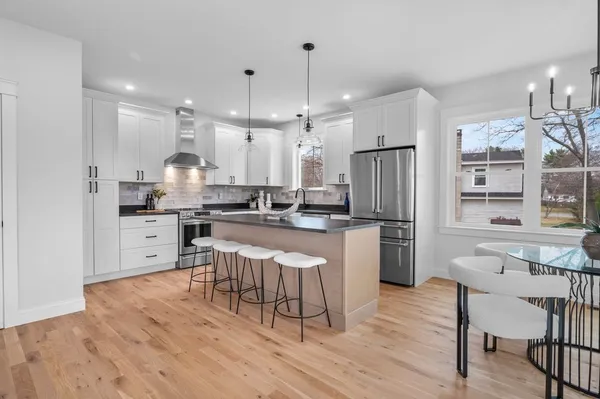 a kitchen with a dining table chairs wooden floor cabinets and stainless steel appliances