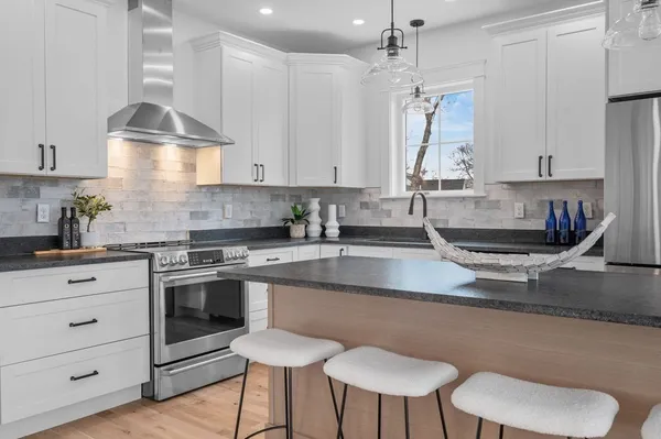 a kitchen with granite countertop a stove a sink and a refrigerator
