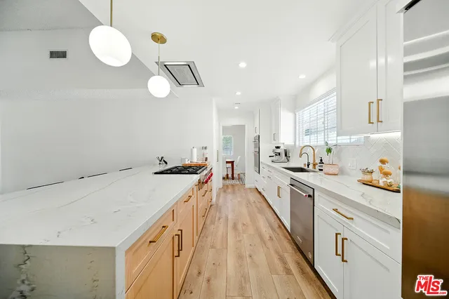 a kitchen with a sink a counter space appliances and cabinets