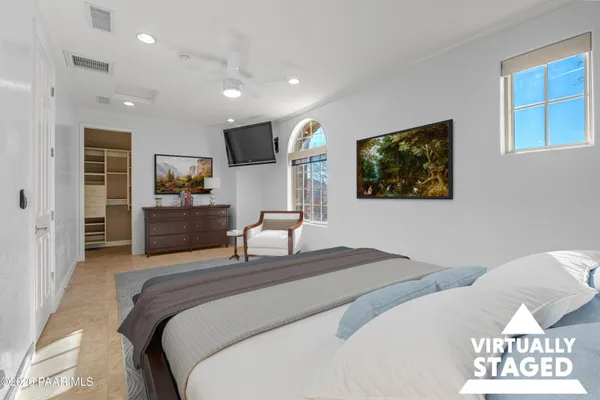 a spacious bedroom with a bed and a flat screen tv