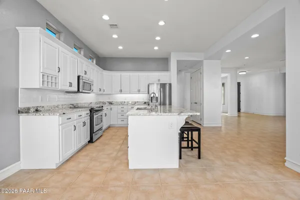 a large kitchen with kitchen island a sink a stove a refrigerator and a dining table with wooden floor