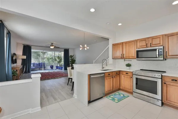a kitchen with stainless steel appliances granite countertop a stove top oven a sink dishwasher a refrigerator and white cabinets with wooden floor