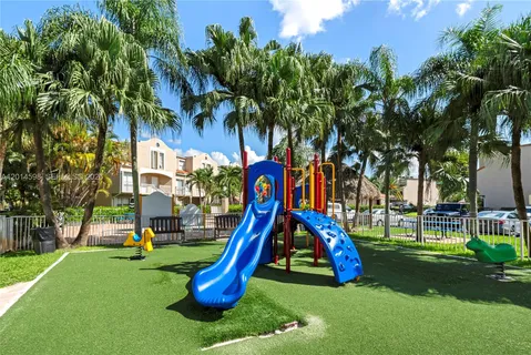a view of a park with slide and a palm tree