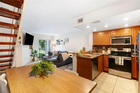a kitchen with stainless steel appliances granite countertop a stove top oven a sink dishwasher a dining table and chairs with wooden floor