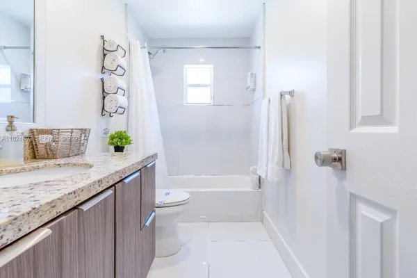 a bathroom with a granite countertop sink a toilet and shower
