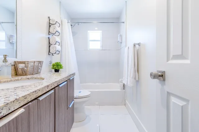 a bathroom with a granite countertop sink a toilet and shower