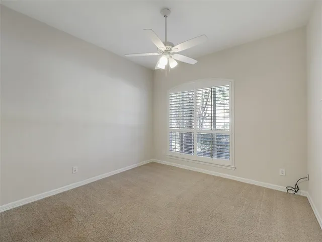 an empty room with a window and a fan