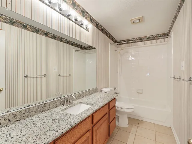 a bathroom with a granite countertop sink a toilet and shower