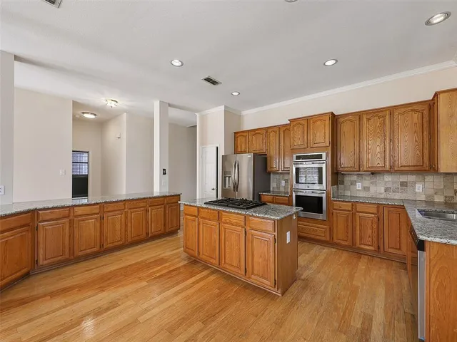 a large kitchen with cabinets wooden floor and stainless steel appliances