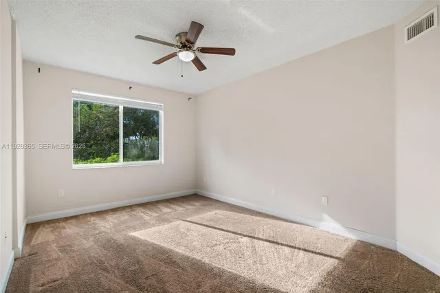 an empty room with ceiling fan and window
