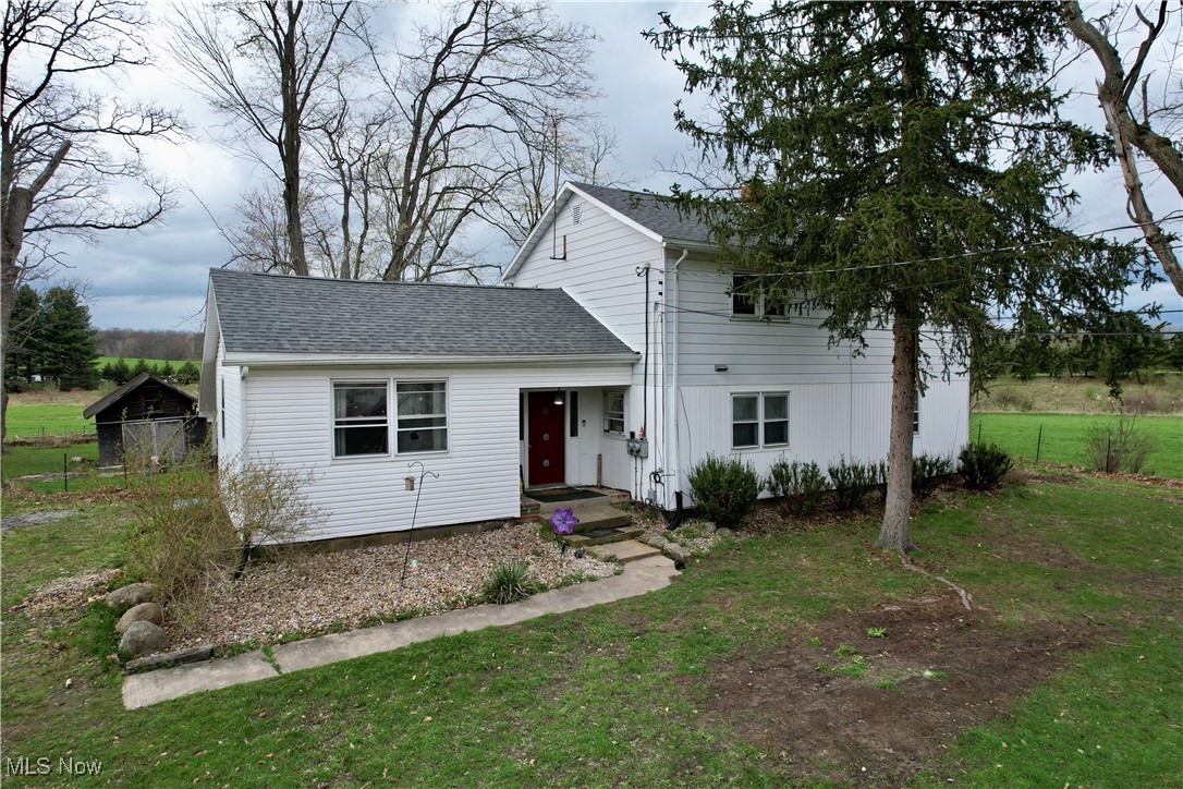 View of front of home with roof with shingles and a front yard