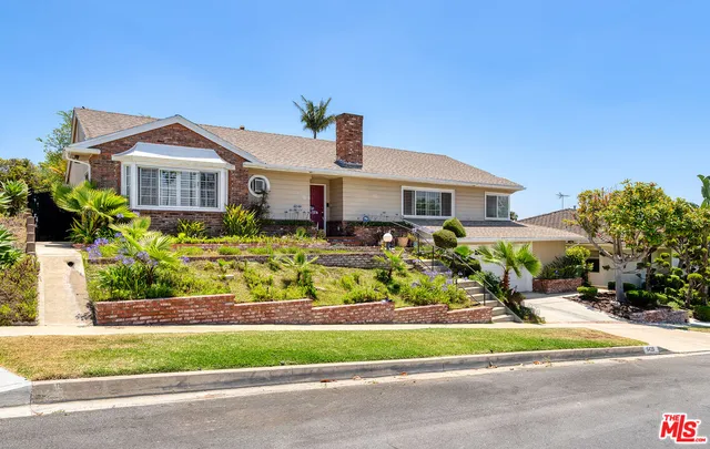 a front view of a house with a yard and potted plants